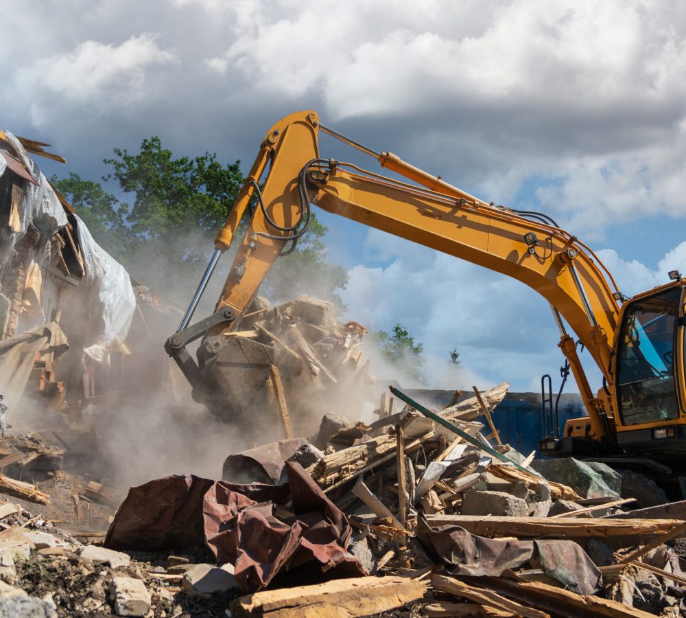 Process of demolition of old building dismantling. Excavator breaking house. Destruction of dilapidated housing for new development.