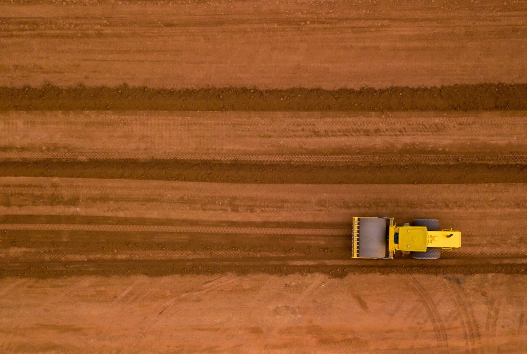 Aerial view yellow excavator building a highway, Road grader heavy earth moving, Bulldozer working at road construction.