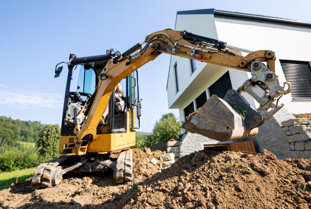 Mini excavator digging preparing ground under home garden