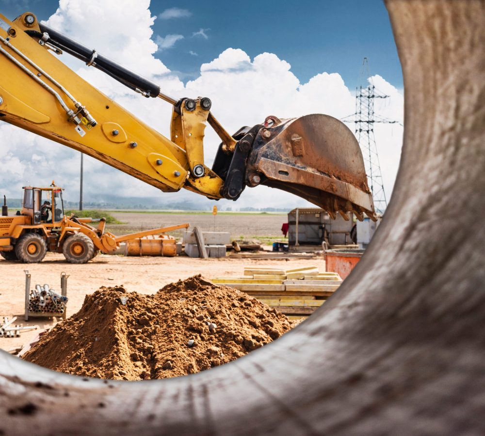 Excavator digs piles. Earthworks for the construction of the foundation. Construction equipment for the device of piles. Preparatory work for grillage. View from a large concrete pipe