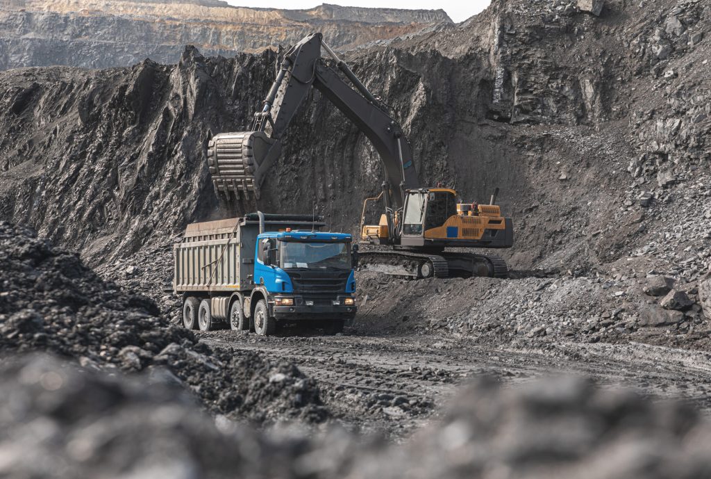 Large quarry dump truck. Big yellow mining truck at work site. Loading coal into body truck. Production useful minerals. Mining truck mining machinery to transport coal from open-pit production.