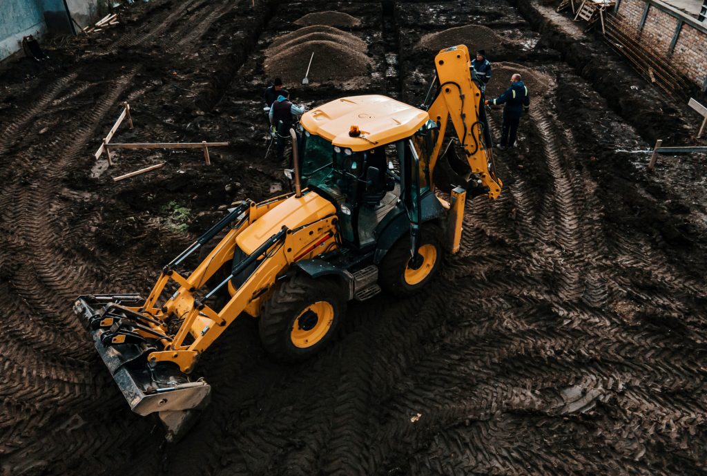 An excavator is digging pit for foundation on a reconstruction site.